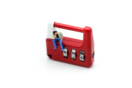 Miniature people : man sitting on metal security lock key.の写真素材