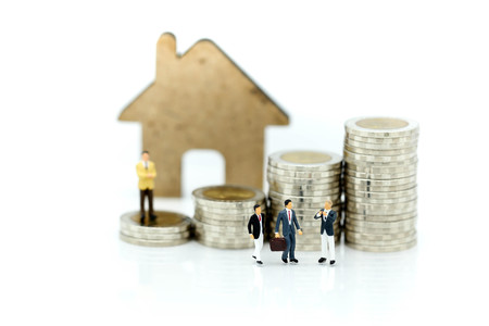 Miniature people : Businessman with paper house and stack of coins.の写真素材