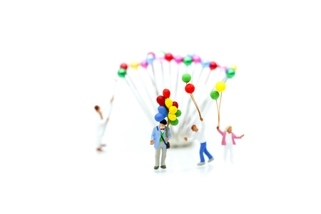 Miniature people : family and children with colorful ballons standing on white background.の写真素材