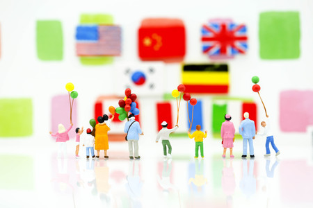 Miniature people : family and children with colorful ballons standing with nation flag background.の写真素材