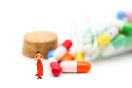Miniature people :  slim body woman standing with tape Measure  and drug background.の写真素材