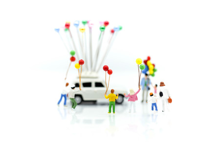 Miniature people : family and children with colorful ballons standing on white background.の写真素材