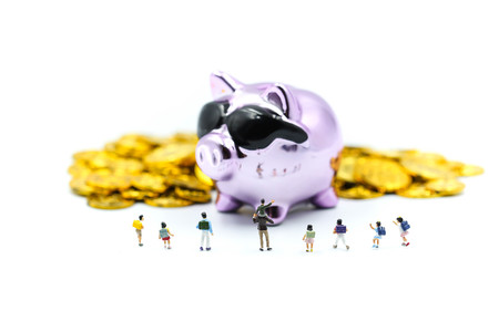 Miniature people : children or student with Purple Piggy bank money  and gold coins.の写真素材