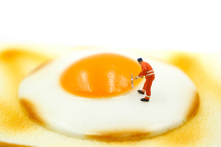 Miniature people : Worker digging on Toast bread with egg on white background.の写真素材
