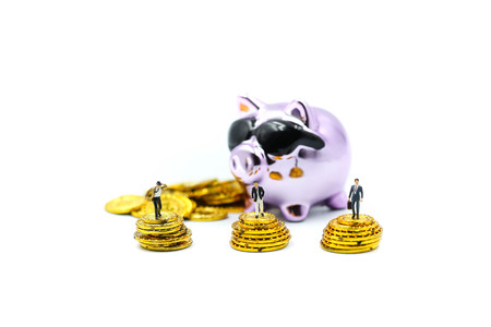 Miniature people : Businessman stand with Purple Piggy bank money  and gold coins.の写真素材