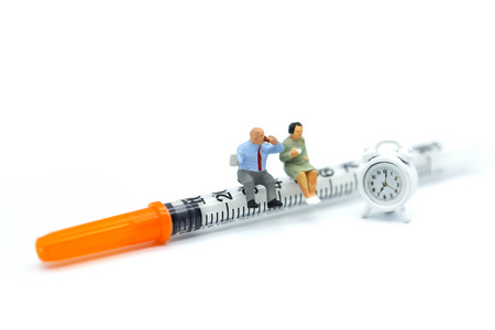 Miniature people : couple sitting on Syringe,healthcare concept.の写真素材