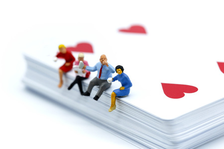 Miniature people : sitting on playing card.