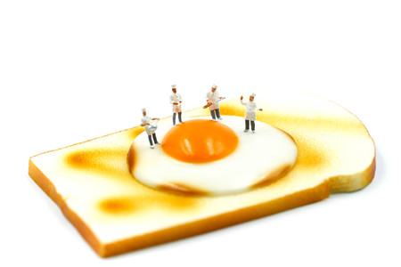 Miniature people : Chef on Toast bread with egg on white background.の写真素材