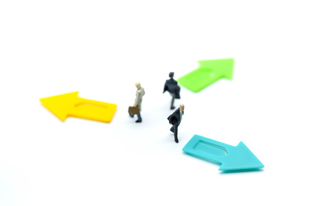 Miniature people: Businessman standing in front of arrow pathway choice using as Business decision...