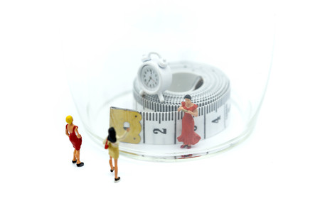 Miniature people : woman with Magnifying glass focusing slim beautiful  woman and tape...