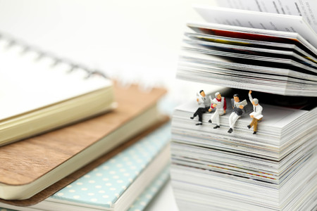 Miniature people: Businessman reading newspaper and sitting on book  using as education or relax business  concept.の写真素材