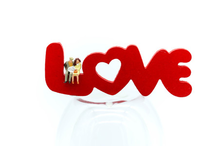 Miniature people : Couple of love sitting with red hearts and wooden text of LOVE,Lover and valentine concept.の写真素材