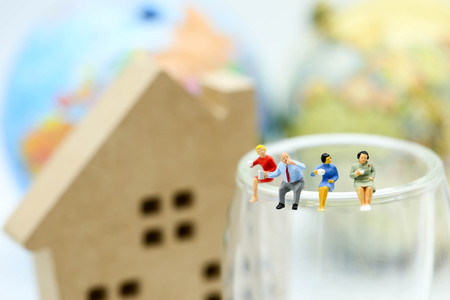 Miniature people: Businessman and woman reading newspaper and sitting on book  using as education or relax business  concept.の写真素材