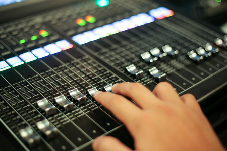 Hands push a Professional audio mixing console with faders and adjusting knobs,TV equipment ,sound...