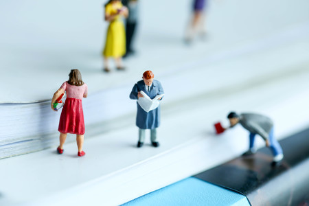 Miniature people : reading stand on book using as background education or business concept.