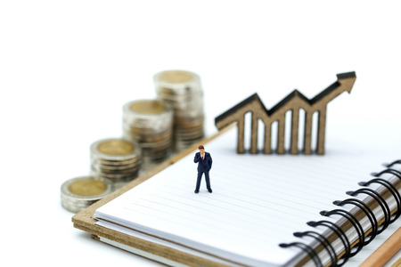 Miniature people : Businessman standing with wooden bar chart icon and stack of coins,Business Vision Concept.の写真素材