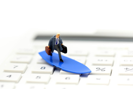 MIniature people : businessman standing on button of calculator. Financial, and business concept.