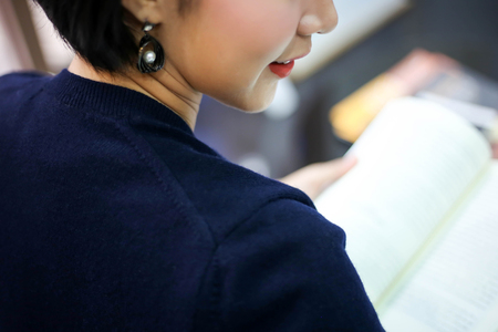 happy young woman beautiful reading a book in a library,people, knowledge, education and school concept.の写真素材