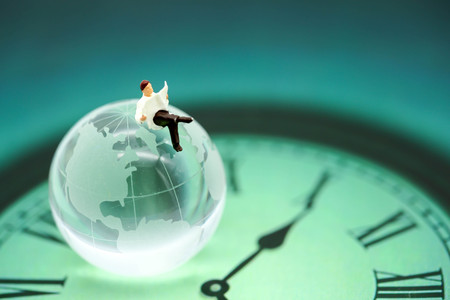 Miniature people : businessman reading newspaper sitting on  global world with the time,Business...