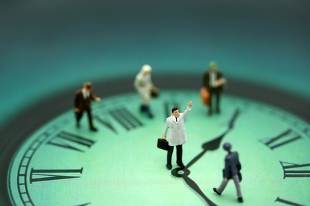Miniature people : business man looking at watch and walk on the clock background, time business concept.の写真素材