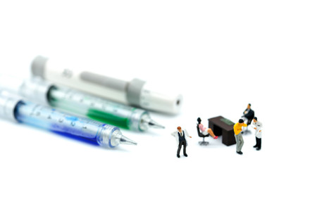 Miniature people: doctor  with stethoscope and syringe and  oldmans sitting using for medical or healthcare background concept.の写真素材