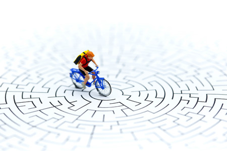 Miniature people : riding bicycle on start point of maze using as background business concept.の写真素材