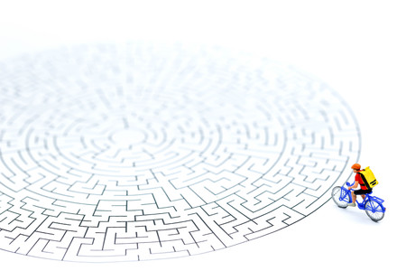 Miniature people : riding bicycle on start point of maze using as background business concept.の写真素材