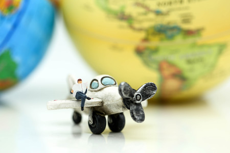 Miniature people : business team, couple of love sitting on airplane wing for travel around the world.の写真素材