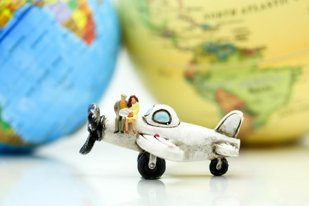 Miniature people : business team, couple of love sitting on airplane wing for travel around the world.の写真素材