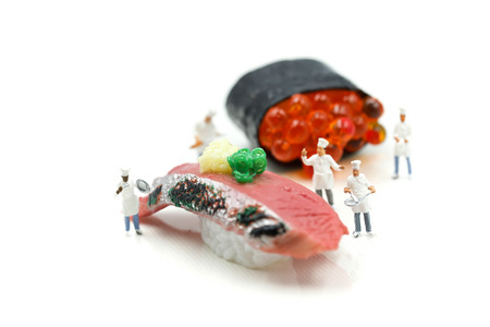 Miniature people : Chef with Salmon egg on sushi nigiri roll on white background.の写真素材