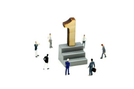 Miniature people : Businessman standing with wooden number of 1,to be the first,Business competition Concept.の写真素材
