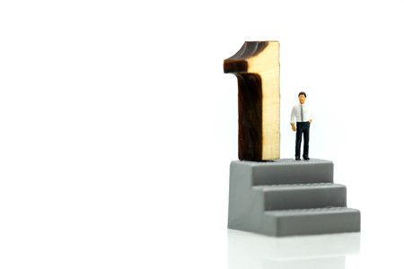 Miniature people : Businessman standing with wooden number of 1,to be the first,Business competition Concept.の写真素材