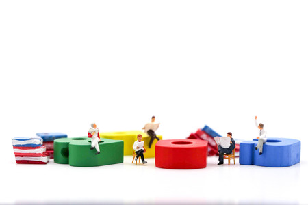 Miniature people : businessman reading a book sitting on Colorful alphabet,education and social background concept.の写真素材