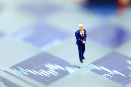 Miniature people : Businessman standing on a graph chart financial analysis review documentの写真素材