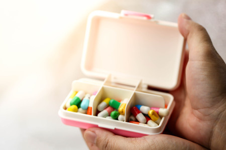 Close up Hand picking up capsule drug from plastic pill box. Health care and medical concept.の写真素材