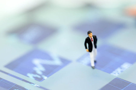 Miniature people : Businessman standing on a graph chart financial analysis review documentの写真素材