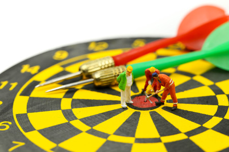 Miniature people : worker digging on the target on dart board, concept of success business.