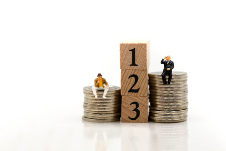 Miniature people : Businessman sitting on stack of coins and wooden of block.