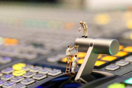 Miniature people : worker painting on switcher control of Television Broadcast,color buttonsの写真素材