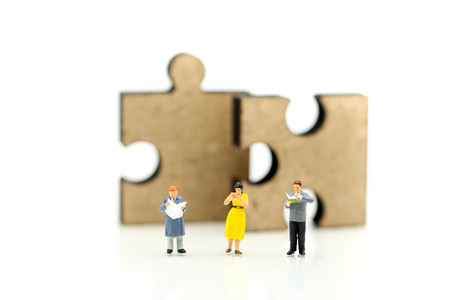 Miniature people :  reading a book and sitting on jigsaw puzzle pieces,Concept of education and reading. The development of the imagination.の写真素材