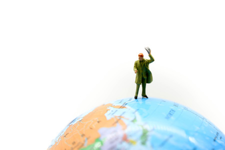 Miniature people : travelers with backpack standing on world map, walking to destination