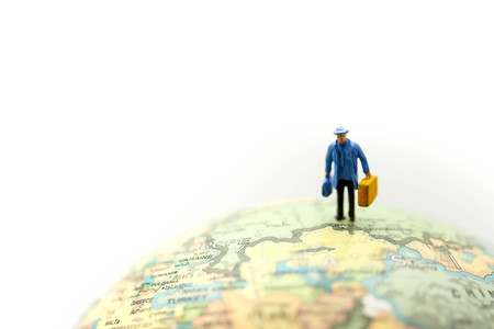 Miniature people : travelers with backpack standing on world map, walking to destinationの写真素材