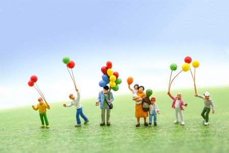 Miniature people with family holding balloon on the map with sunlight, happy family day concept.の写真素材