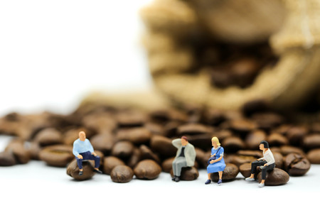 Miniature people : people sitting on Roasted coffee beans using for concept of Cappuccino Day.の写真素材