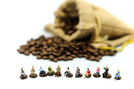 Miniature people : people sitting on Roasted coffee beans using for concept of Cappuccino Day.の写真素材