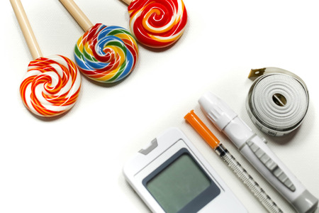 Sweet candy with Insulin syringe,lancet,test strip,glucose meter and lancing device concept of diabetes and reduction of eating sweetsの写真素材