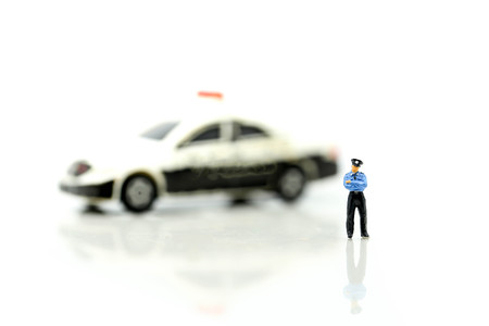Miniature people : Police officer emergency service car driving street.