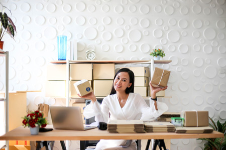 Young asian girl is freelancer Start up small business owner writing address on cardboard box at...