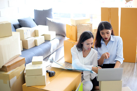 Young asian girl is freelancer Start up small business owner writing address on cardboard box at...