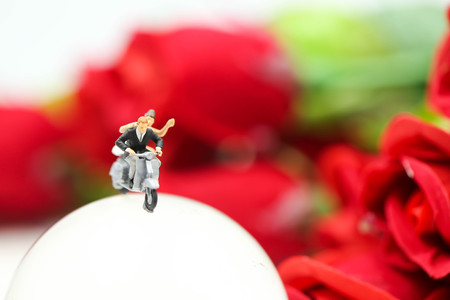 Miniature people : Couple of love riding the motorcycle on The Globe with rose background.の写真素材